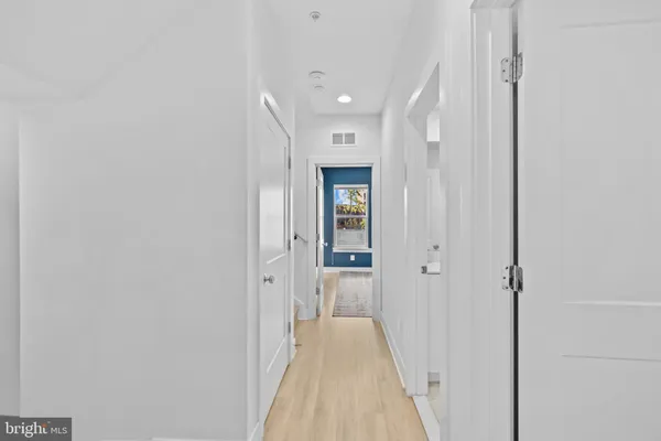 a view of a hallway with wooden floor and a bathroom