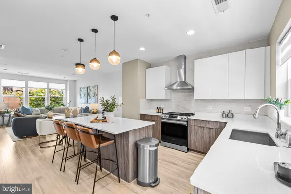 a kitchen with stainless steel appliances granite countertop a stove a sink a microwave a dining table and chairs with wooden floor