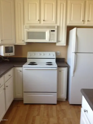 a kitchen with granite countertop white cabinets and white appliances