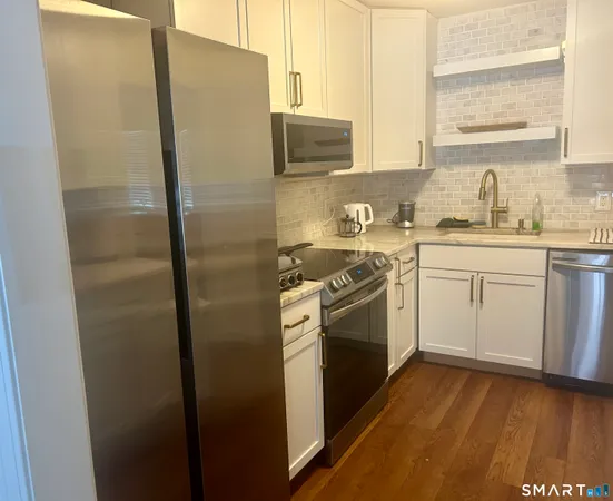 a kitchen with stainless steel appliances a refrigerator sink and white cabinets