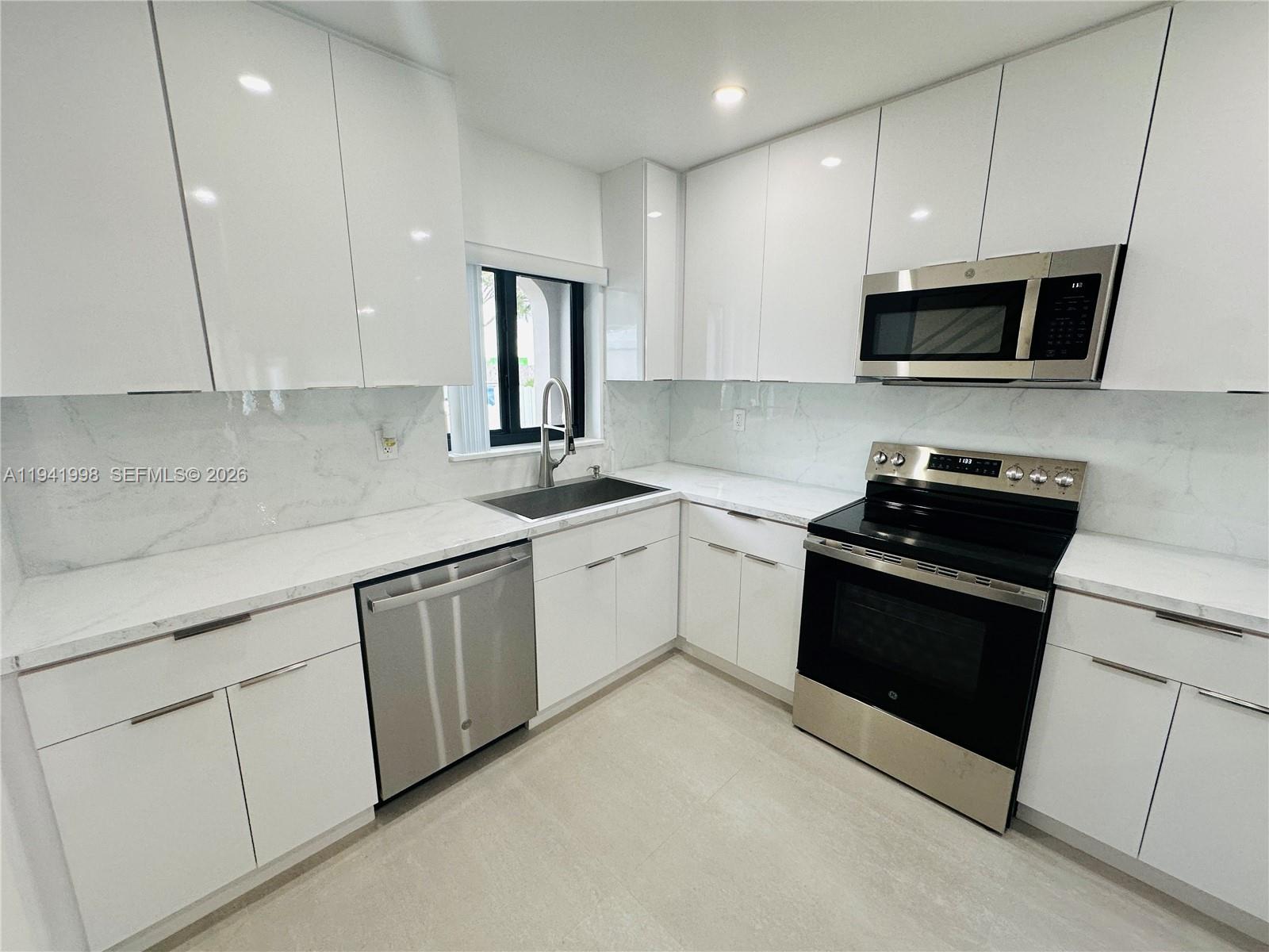 7157 West 19th Court, Unit 7157 Hialeah, FL 33014 - Photo 7 of 40 a kitchen with stainless steel appliances granite countertop a sink dishwasher a stove and a microwave oven with cabinets