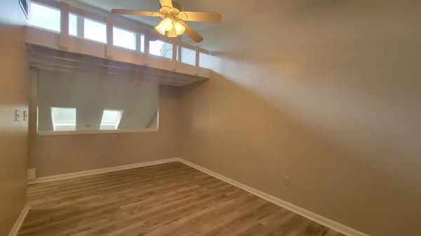 a view of a hallway with wooden floor and windows