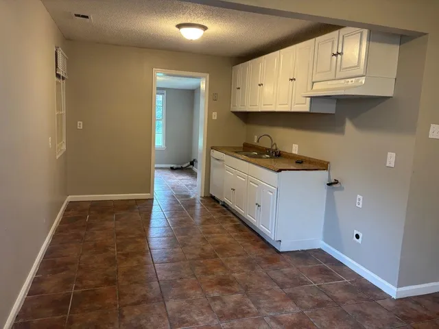 a kitchen with granite countertop a stove top oven a sink a refrigerator and cabinets