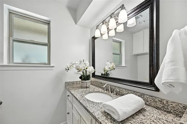 a bathroom with a granite countertop sink and a mirror