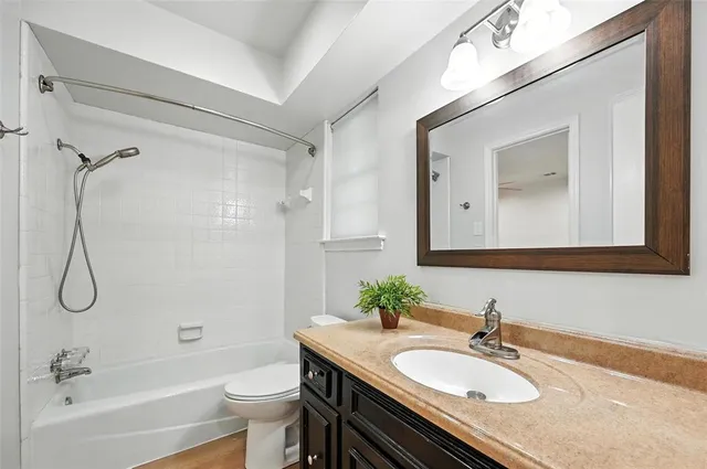 a bathroom with a granite countertop sink toilet a mirror and shower