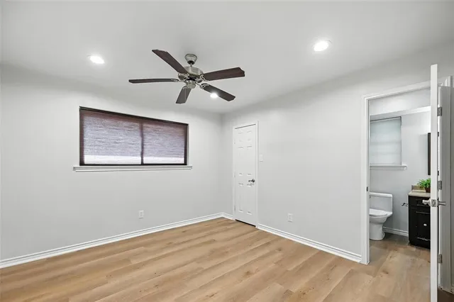 an empty room with wooden floor and a ceiling fan