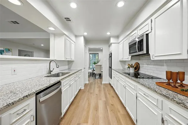 a large kitchen with stainless steel appliances granite countertop a lot of counter space and wooden floors