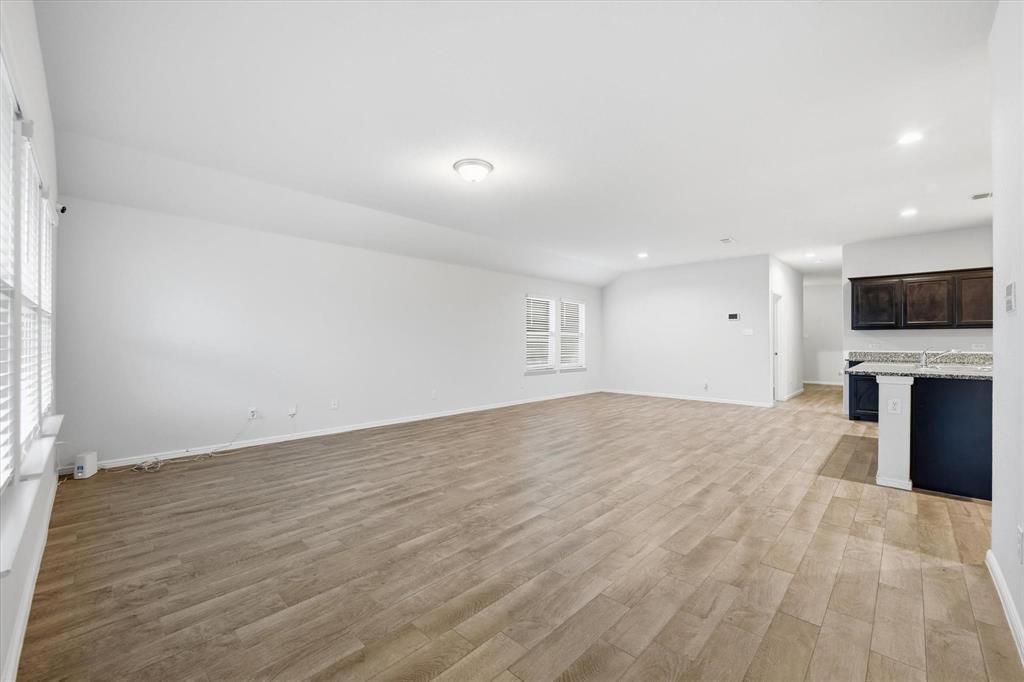 9308 Desertrock Road Fort Worth, TX 76131 - Photo 4 of 29 an empty room with a flat screen tv and kitchen view