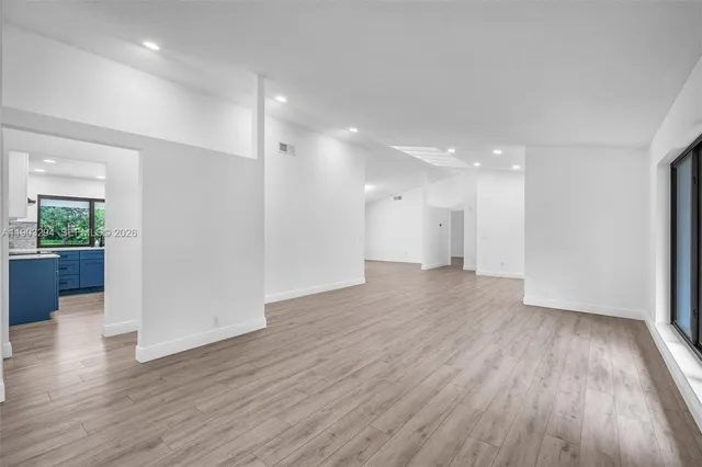 a view of a big room with wooden floor and windows