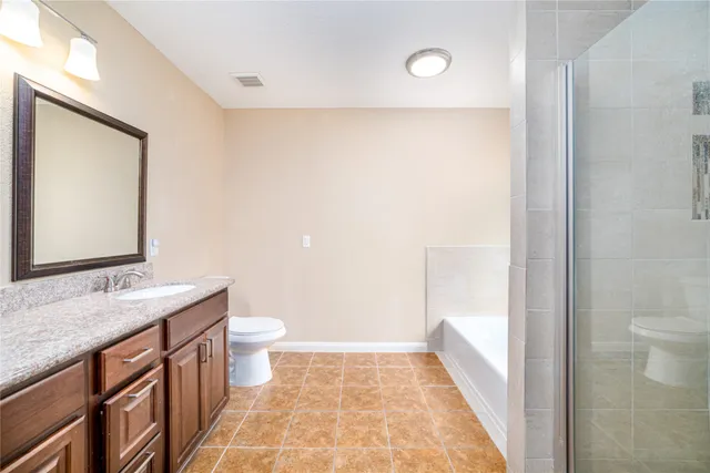 a bathroom with a granite countertop sink a toilet a mirror and shower