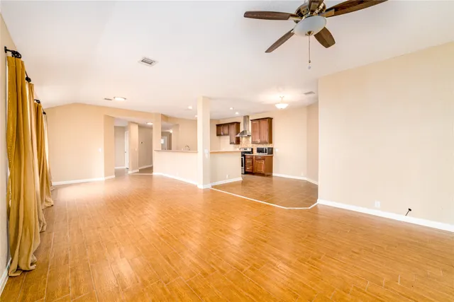a view of empty room with wooden floor and fan