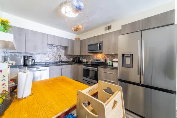 a kitchen with stainless steel appliances granite countertop a refrigerator a sink and a stove