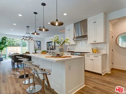 a kitchen with stainless steel appliances granite countertop a sink a stove a refrigerator and island with wooden floor
