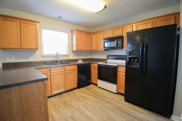 a kitchen with stainless steel appliances granite countertop a refrigerator a sink dishwasher a stove top oven a refrigerator and cabinets