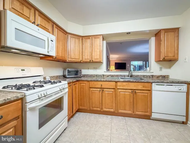 a kitchen with stainless steel appliances granite countertop a refrigerator a sink dishwasher a stove with wooden cabinets and floor