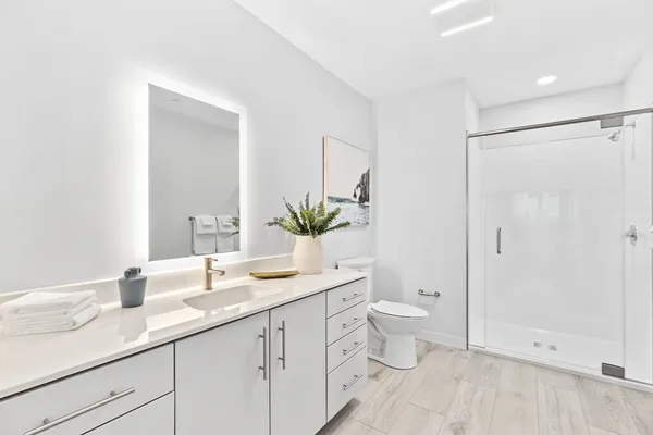 a bathroom with a granite countertop sink a toilet and a large mirror