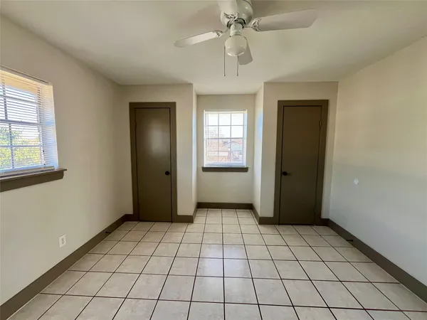 a view of an empty room with window and chandelier fan