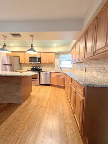 a kitchen with stainless steel appliances granite countertop a sink stove and wooden cabinets