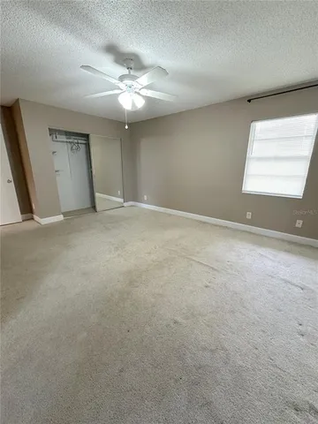 a view of an empty room with a chandelier fan