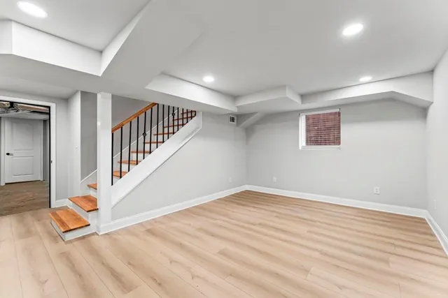 a view of an empty room with wooden floor and windows