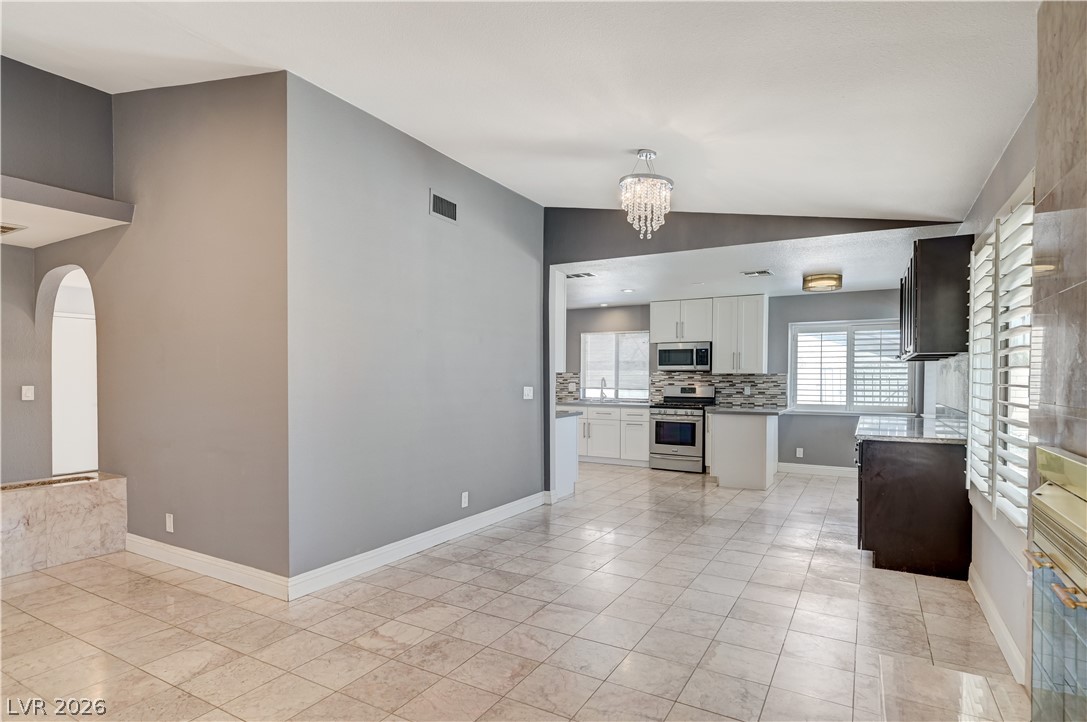 6635 Costa Brava Road Las Vegas, NV 89146 - Photo 59 of 59 An open floorplan seamlessly connects a sleek kitchen with a spacious living area, featuring tiled flooring.
