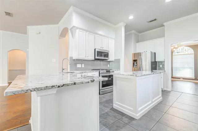 a kitchen with granite countertop white cabinets and stainless steel appliances