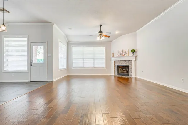 an empty room with wooden floor fireplace and windows