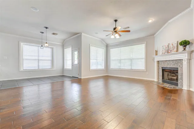 an empty room with wooden floor fireplace and windows