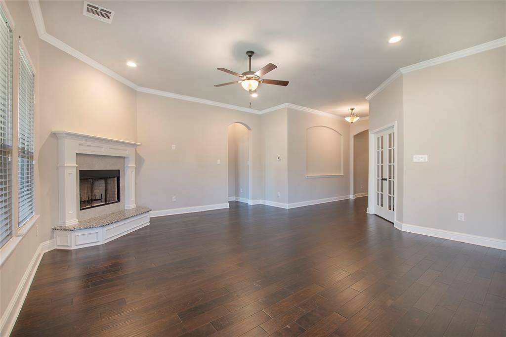 2811 Diamond Ridge Drive Arlington, TX 76001 - Photo 12 of 35 an empty room with wooden floor fireplace and a kitchen view