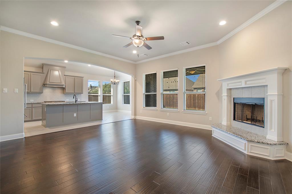 2811 Diamond Ridge Drive Arlington, TX 76001 - Photo 10 of 35 an empty room with wooden floor a kitchen view and a fireplace