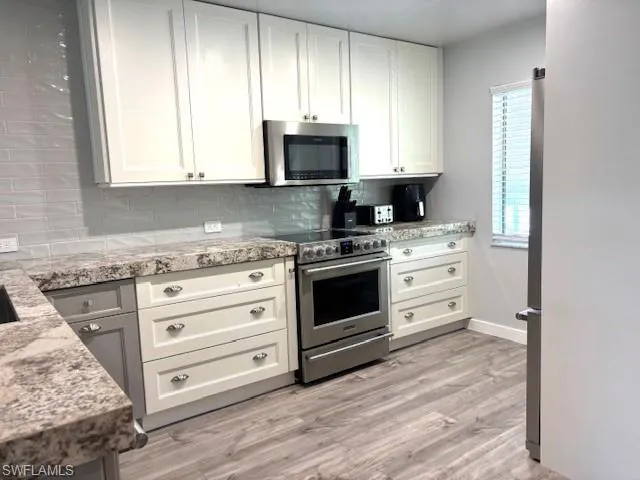 a kitchen with stainless steel appliances white cabinets and a stove top oven