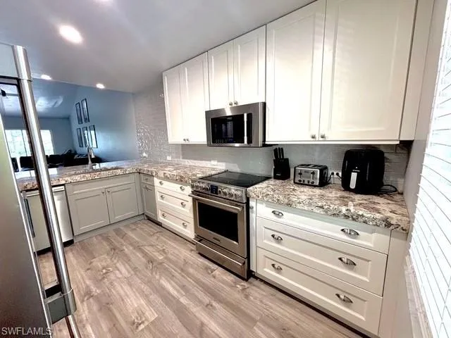 a kitchen with granite countertop a sink stainless steel appliances and white cabinets