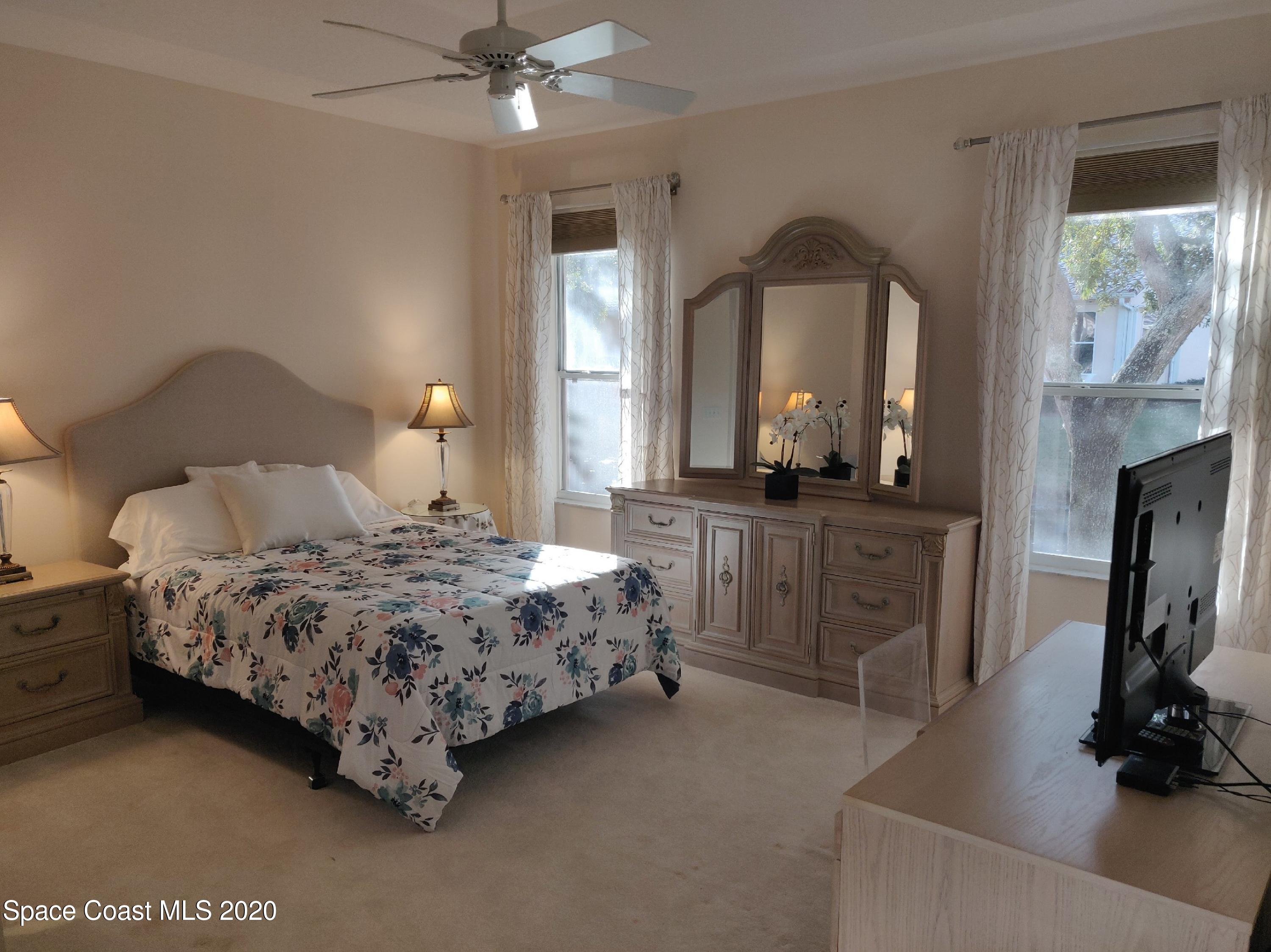 421 Shell Cove Drive Melbourne, FL 32940 - Photo 17 of 23 a bedroom with a bed a mirror on dresser and a large window