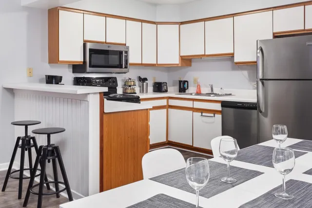a kitchen with stainless steel appliances granite countertop a stove a refrigerator a sink a microwave and chairs