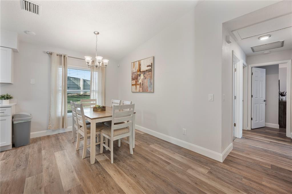1106 Lakewood Road Lakeland, FL 33805 - Photo 7 of 27 a dining room with wooden floor a chandelier a wooden table and chairs