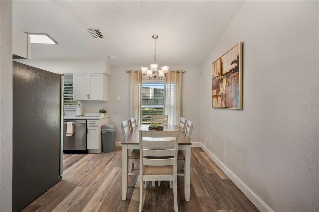 1106 Lakewood Road Lakeland, FL 33805 - Photo 8 of 27 a kitchen with a refrigerator a sink dishwasher a dining table and chairs with wooden floor