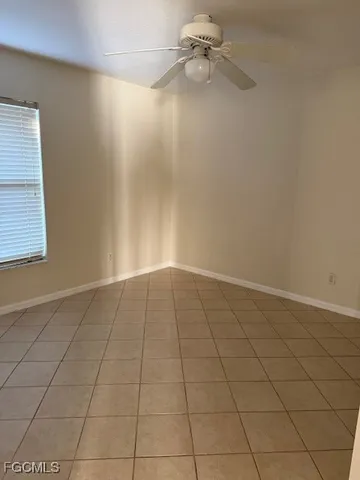 an empty room with a ceiling fan and window