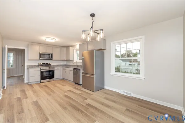 a kitchen with granite countertop stainless steel appliances a refrigerator cabinets and wooden floor