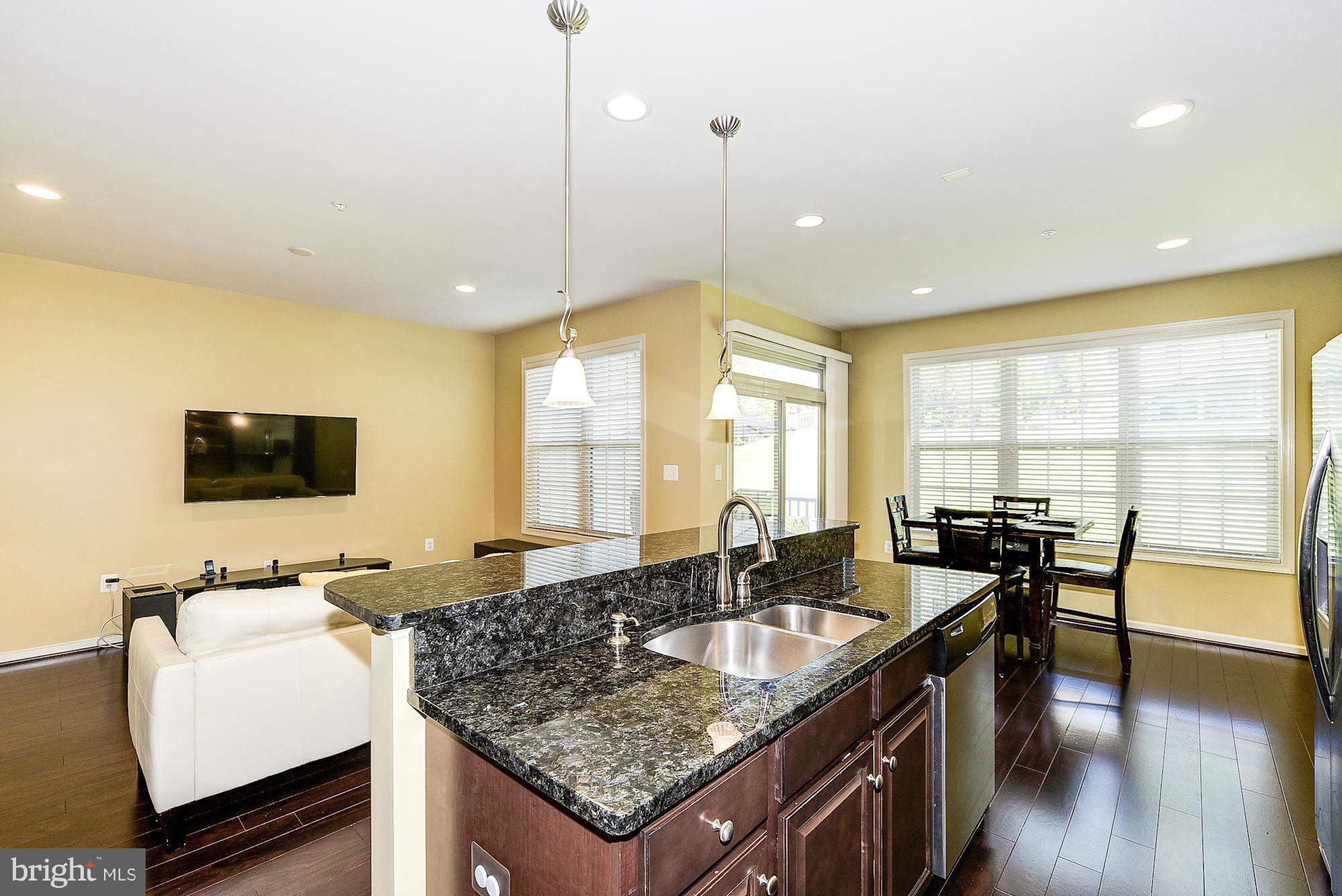 1525 Rabbit Hollow Place Silver Spring, MD 20906 - Photo 12 of 30 a kitchen island with granite countertop a sink a counter top space and living room view