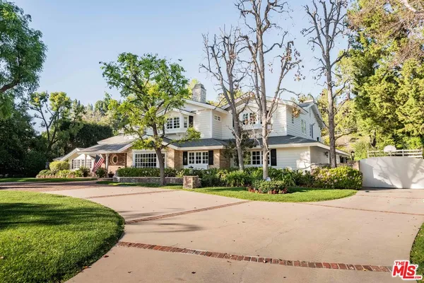 a front view of a house with a garden and trees