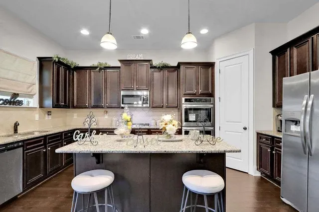 a kitchen with granite countertop a sink refrigerator and cabinets