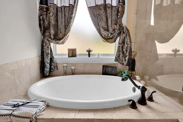 a white bath tub sitting next to a white sink and a mirror