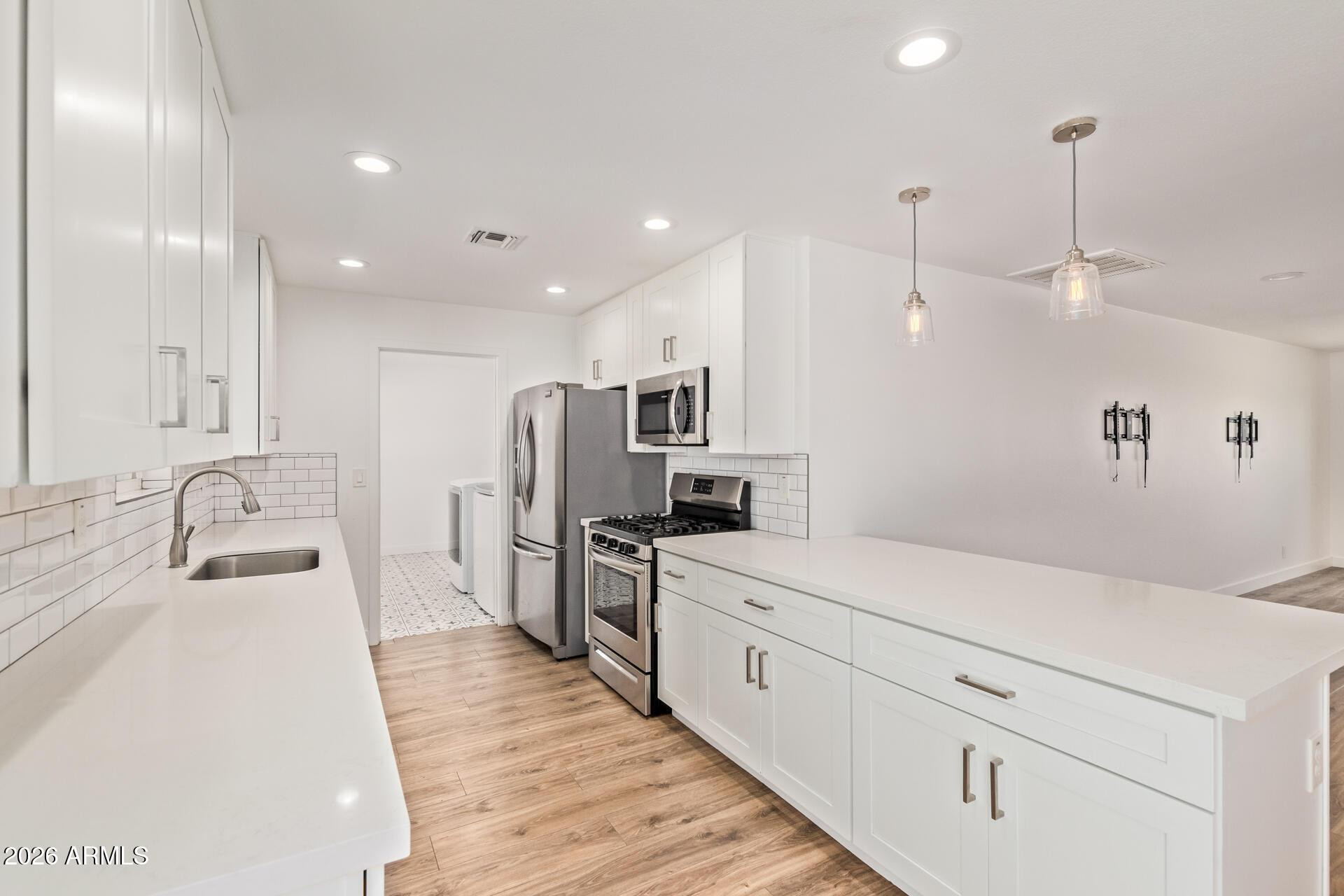 1809 East Concorda Drive Tempe, AZ 85282 - Photo 7 of 23 a kitchen with white cabinets and stainless steel appliances
