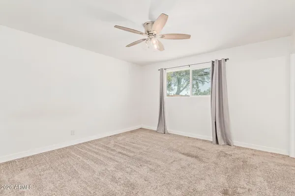 an empty room with windows and fan