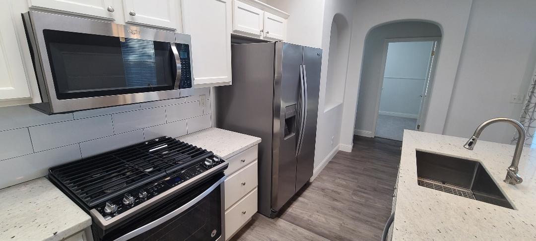 1611 North Monaco Lane Clovis, CA 93619 - Photo 4 of 16 a kitchen with stainless steel appliances kitchen island a stove and a microwave