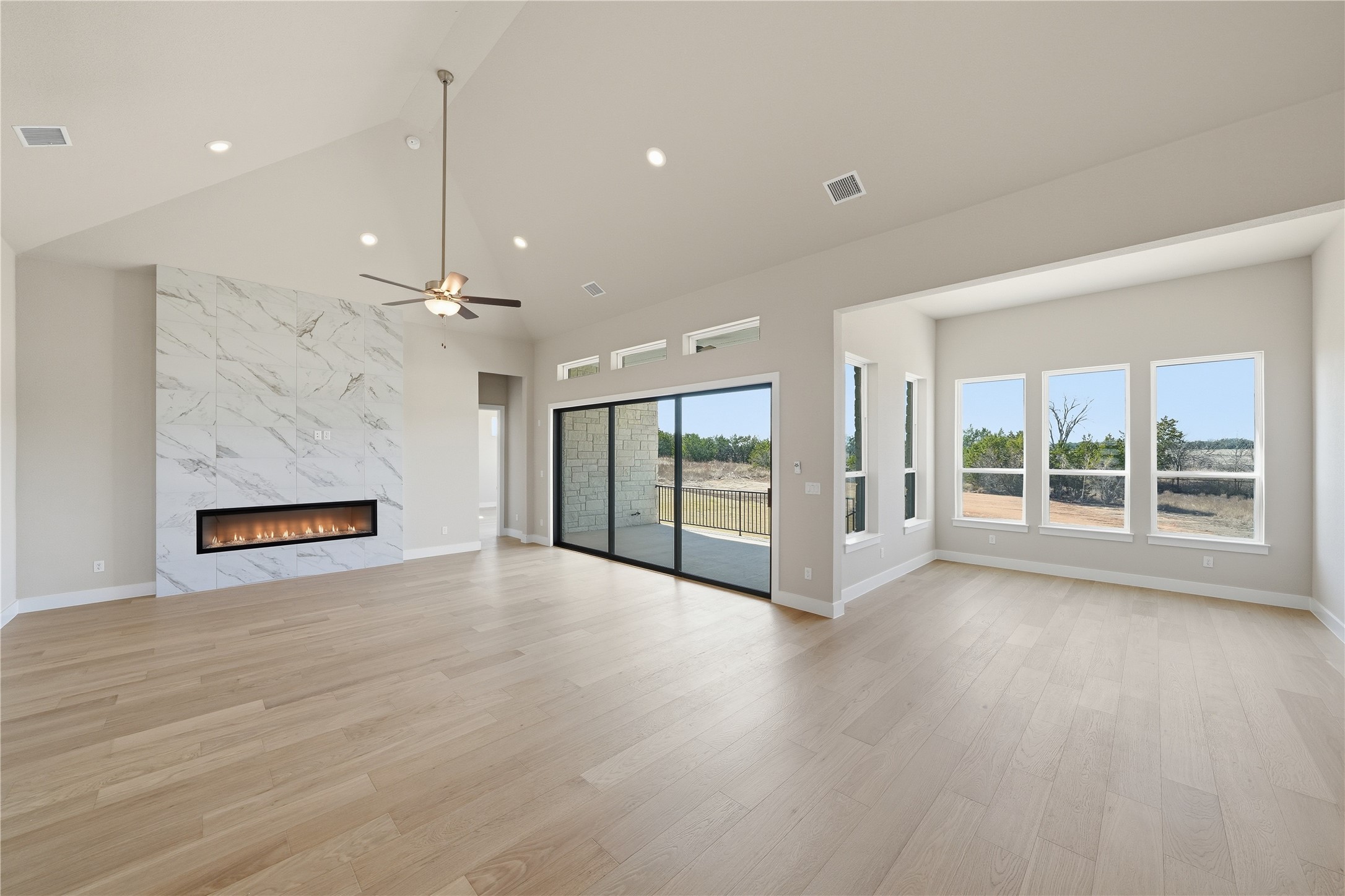 1209 Doelling Drive Georgetown, TX 78633 - Photo 5 of 31 Unfurnished living room featuring a fireplace, light wood-type flooring, lofted ceiling, and a ceiling fan