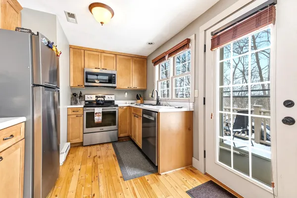 a kitchen with granite countertop a refrigerator a sink a stove top oven and a dishwasher next to a window