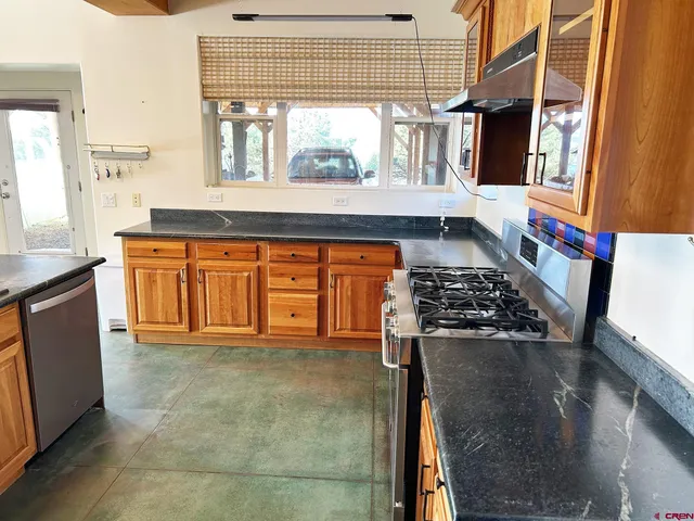a kitchen with stainless steel appliances granite countertop a stove a sink and a microwave