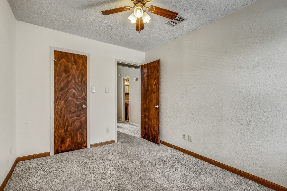 1010 West Rundberg Lane, Unit 24 Austin, TX 78758 - Photo 11 of 24 Unfurnished bedroom with carpet floors, a textured ceiling, ceiling fan, and baseboards