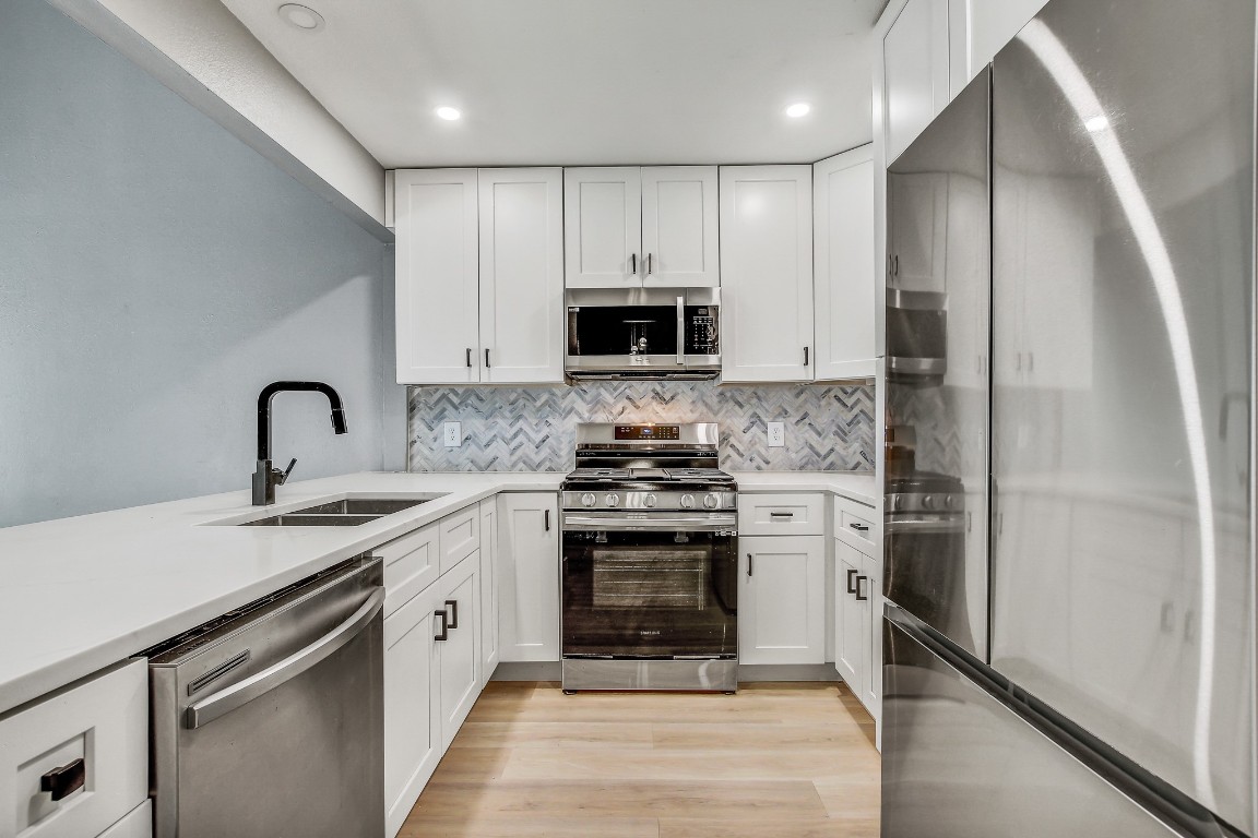 1010 West Rundberg Lane, Unit 24 Austin, TX 78758 - Photo 2 of 24 Kitchen with appliances with stainless steel finishes, a sink, white cabinets, and recessed lighting